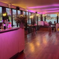 Salon d’une péniche aux grandes baies vitrées, au bord de la Seine